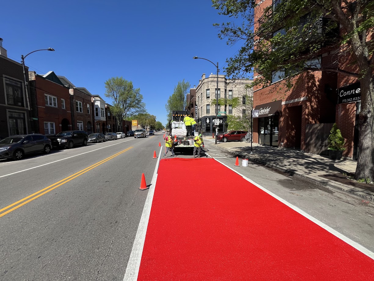 Crews installing red bus only paint on Chicago Avenue